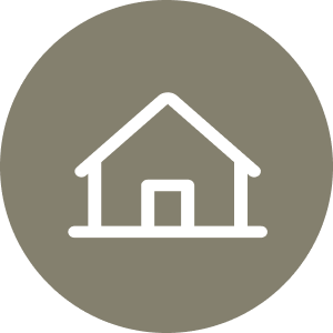 Icon of a simple house with a triangular roof and rectangular base in white, centered on a gray circle background.