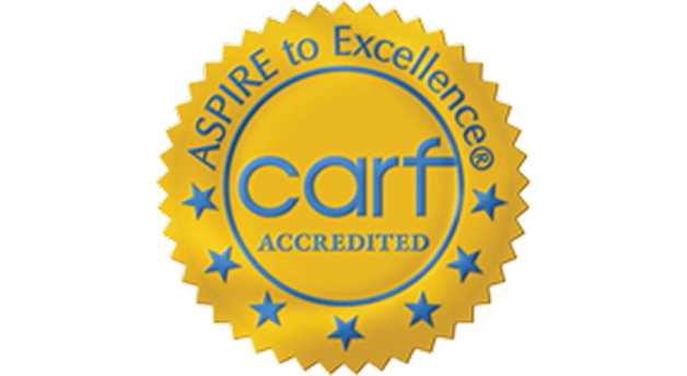 Gold seal with scalloped edges featuring the text ASPIRE to Excellence at the top, carf in the center, and ACCREDITED below. Blue stars encircle the inner edge.